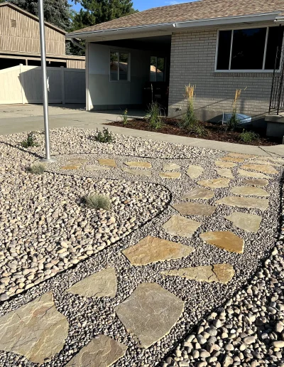 Front yard with gravel landscaping, stone walkway, and a brick house entrance.